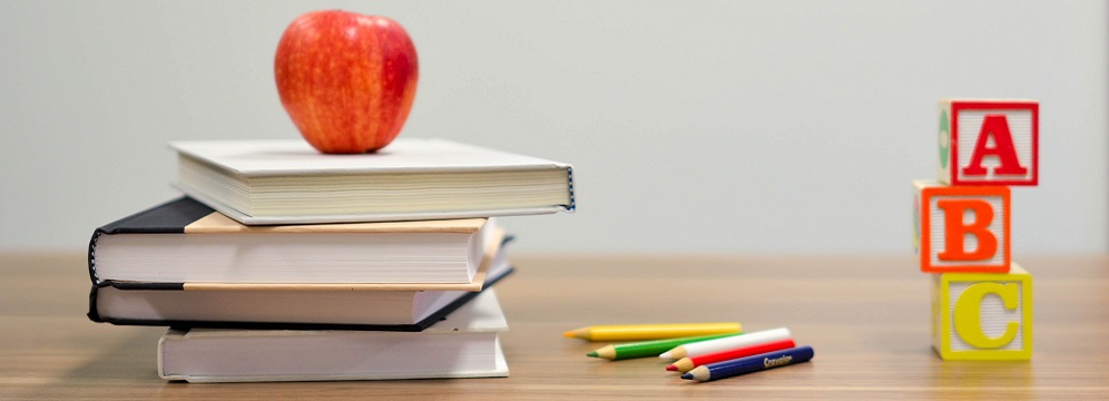 Staplade skolböcker med ett rött äpple på toppen