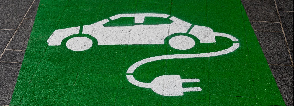 Bild på en grön matta med en bil samt laddsladd.