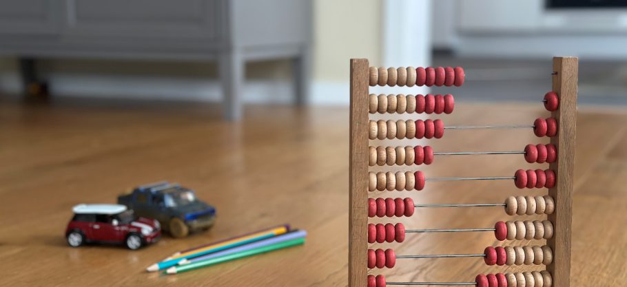 Bild på några leksaker och penna på ett parkettgolv.